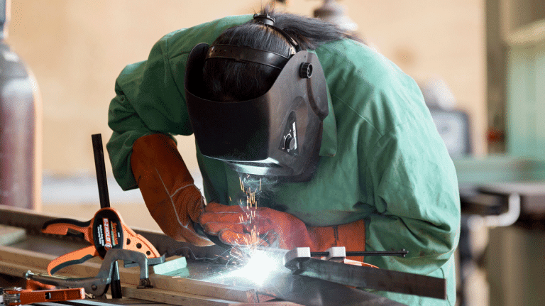 Furniture design student Lacey Campbell welds while wearing protective garments