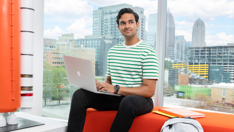 student working on computer with skyline in background