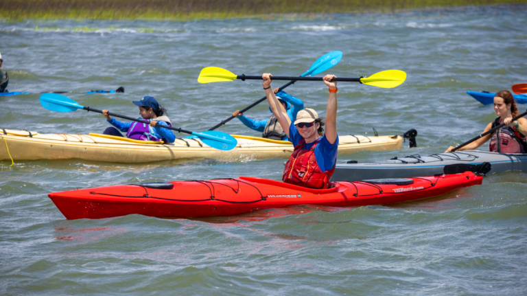 Students kayaking down a river on an outdoor recreation excursion.