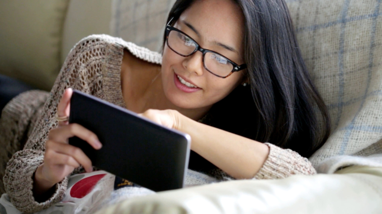 Lounging woman looks at tablet