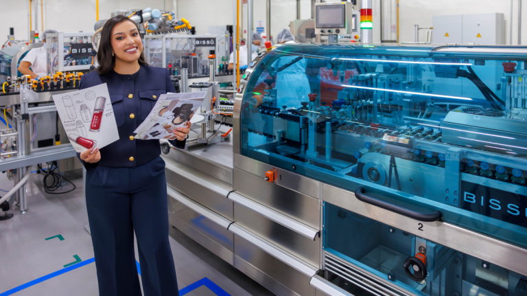 Business of beauty and fragrance alum works beside production equipment.