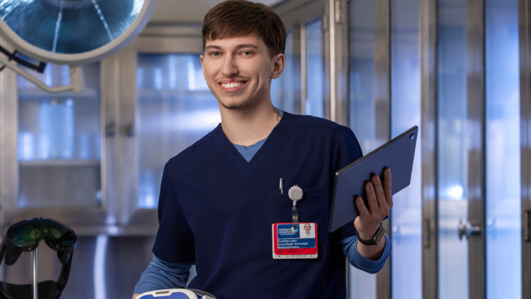Extended reality alum in navy medical scrubs holds a VR headset in a modern clinical setting.