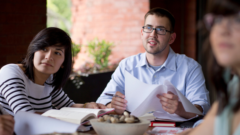 Writing students reviewing work around table