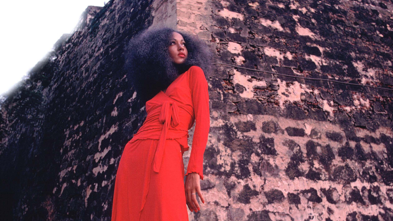 Pat Cleveland in red two-piece matte jersey skirt with wrap top and matching red stockings and shoes