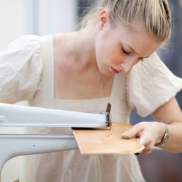 Accessory design student cutting leather Accessory design student using machine to cut leather