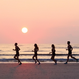 SCAD cross country athletes run across beach at sunset