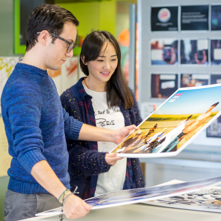 Advertising students looking at print designs Advertising students looking at print designs