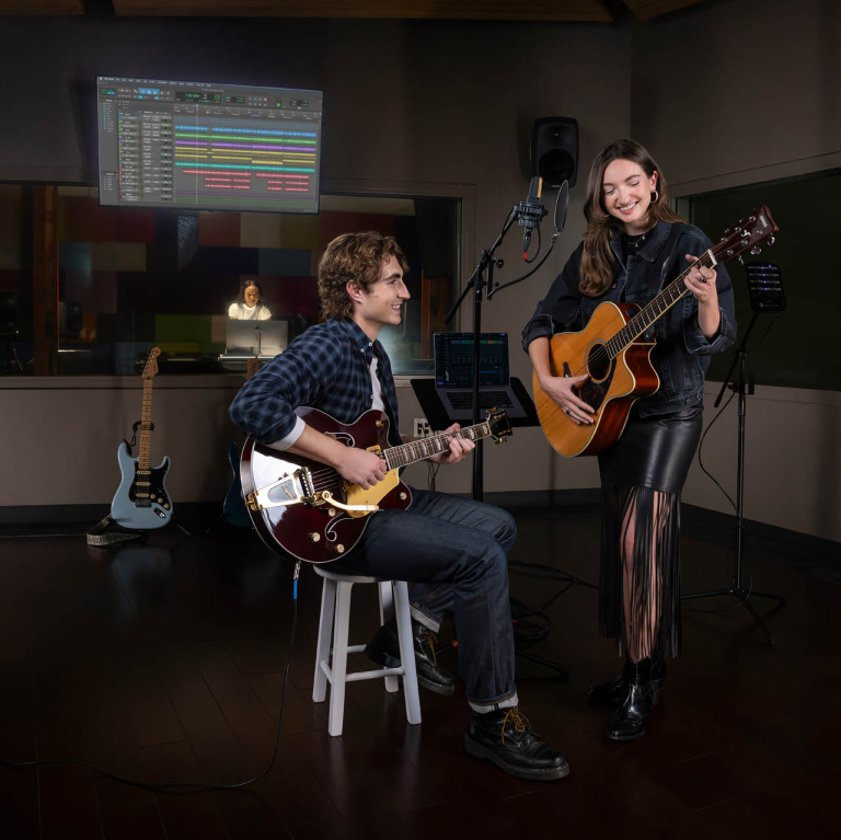 Two students on guitar in recording room.
