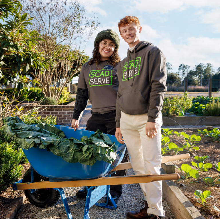 SCAD SERVE volunteers collect greens in a wheelbarrow 
