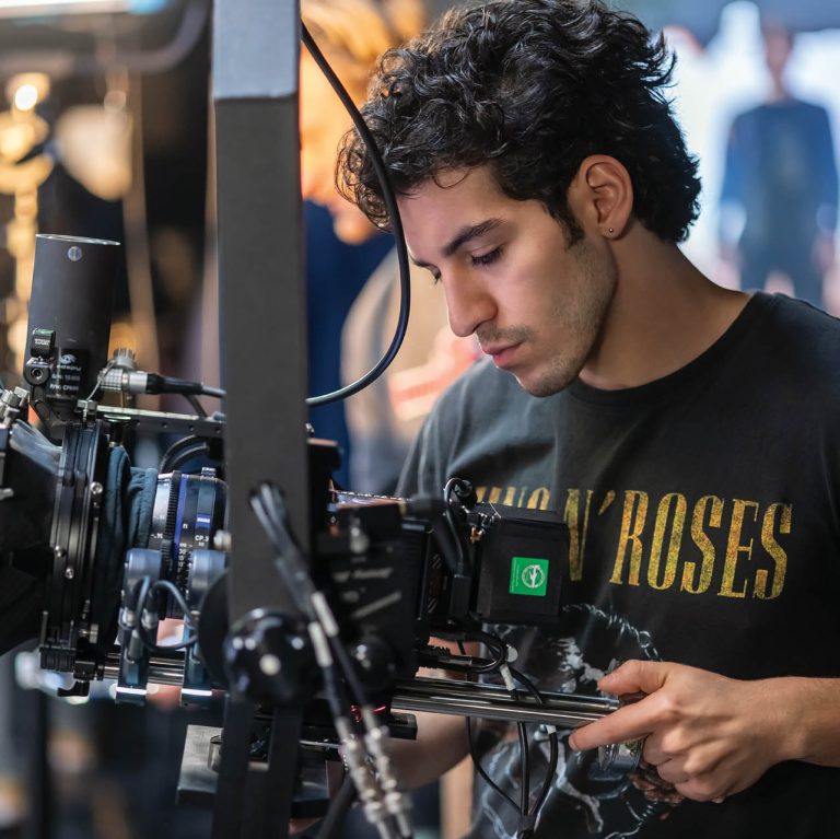 A student operates a professional video camera during a production shoot.