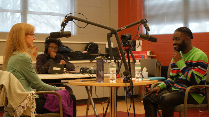 Three people around a table recording stories.