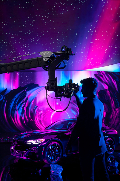 Student films car on LED volume stage against purple and magenta background.