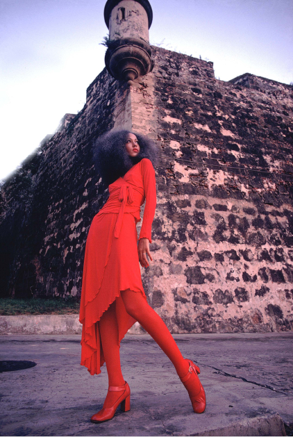 Pat Cleveland in red two-piece matte jersey skirt with wrap top and matching red stockings and shoes